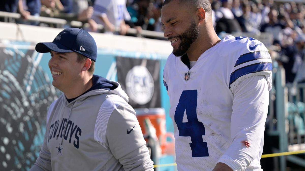 Offensive coordinator Kellen Moore leaves the field with Dak Prescott during a game in the 2022 season.