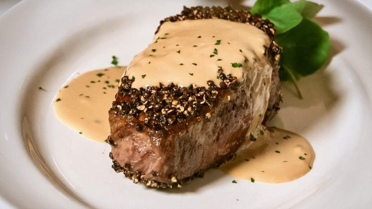 One of the Capital Grille chain’s signature dishes is a dry-aged New York strip au poivre with flaming Courvoisier-cream sauce.