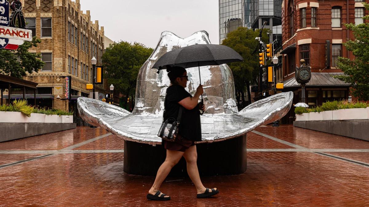 Fort Worth resident Nicolette Cervantez walks across the ‘disco cowboy hat’ in the rain in Sundance Square in downtown Fort Worth on Tuesday, Sept. 3, 2024.
