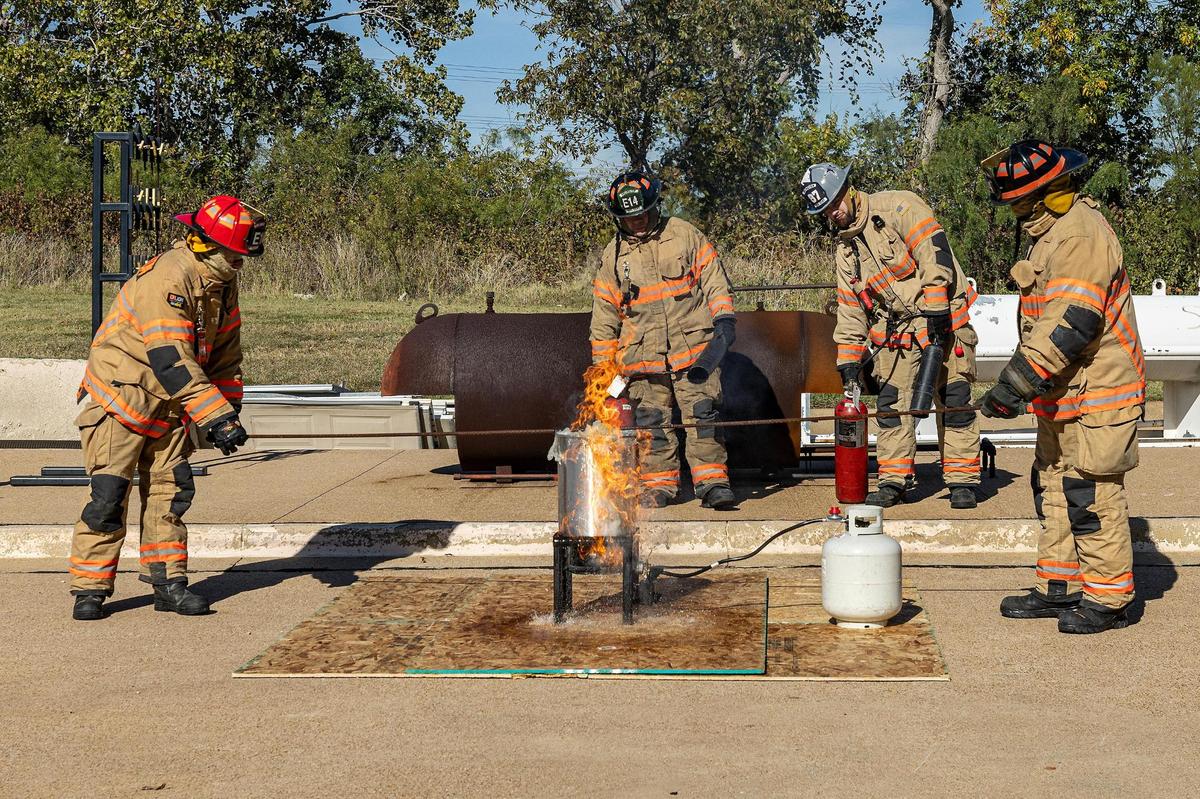 Lieutenant Monty Stayner, left, firefighter Jeremy Contreras, second from left, Dallas Cowboys tight end Jake Ferguson, second from right and firefighter Lonnie Ballenger throw a frozen turkey into hot frying oil for a Turkey Fryer Fire Safety demonstration at the Arlington Fire Department Training Facility Station 14 in Arlington on Tuesday, Nov. 14, 2024.