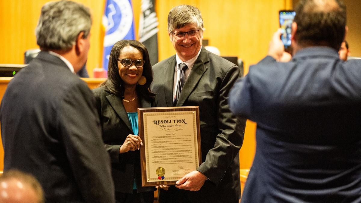 Tarrant County Commissioner Alissa Simmons, left, and Tarrant County criminal courts administrator Gregory Shugart, right hold a proclamation during a Tarrant County Commissioners Court meeting on Tuesday, June 18, 2024. Shugart was awarded a proclamation for his service and efforts in the community’s justice system.