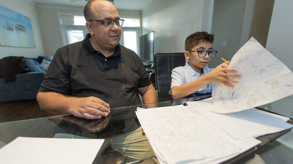 Ryan Ben Alaya, 11, shows his father Hakim Ben Alaya one of the cartoons he has been working on Tuesday, Dec. 16, 2025.