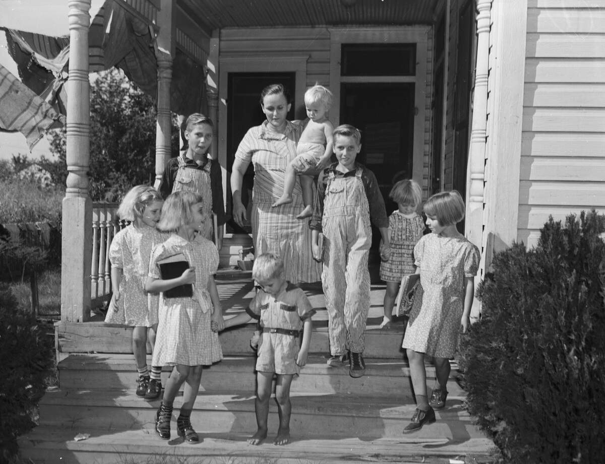 Sept. 9, 1940: Mrs. C.K. Brantley is running through a first day of school dress rehearsal with her eight children. Mrs. Brantley has the children trained to dress for school in 20 minutes. They are Carl (13), Homer (12), Vera (9), Geraldine (8), Billy Jo (7), and Lester Julius (5). Mary Alice (4), is at the far right holding her brother Homer’s hand. Mrs. Brantley is holding her 2-year-old daughter, Lillian Joyce.