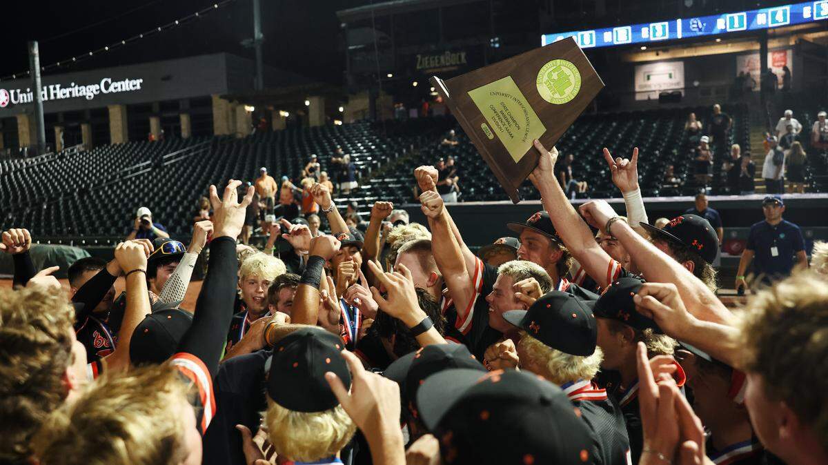 Aledo players break out of a huddle while a player holds up the championship trophy after the Class 5A Division I playoffs state championship game at Dell Diamond Stadium on Friday, June 6, 2025.