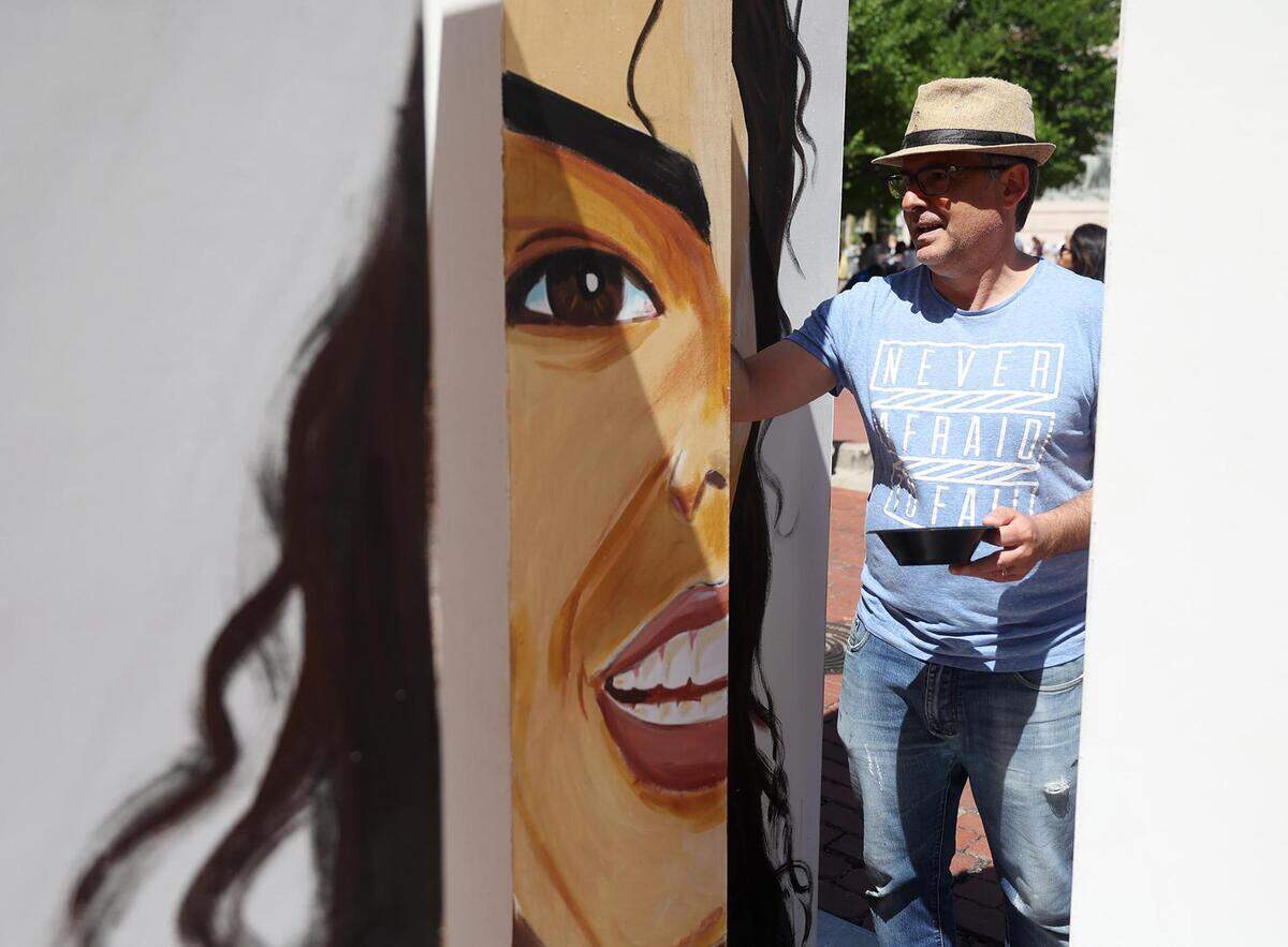 Artist Tony Ortiz paints a multidimensional structure that features four portraits as the Main Street Arts Festival goes on around him on Friday, April 21, 2023.