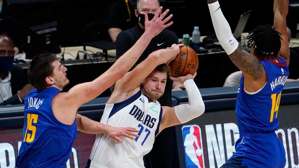 Dallas Mavericks guard Luka Doncic (77) is pressured by Denver Nuggets center Nikola Jokic (15) and guard Gary Harris (14) during the first quarter of an NBA basketball game Thursday, Jan. 7, 2021, in Denver. (