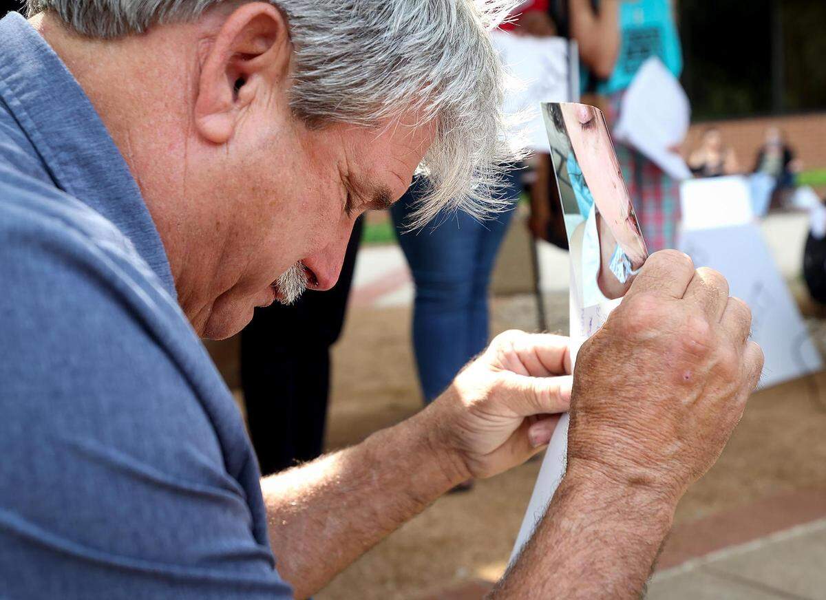 Danny Masten holds photographs of his daughter, Kelly Masten, while taking a moment of silence during a rally outside the Tarrant County Commissioners meeting on Tuesday, May 10, 2022. Kelly Masten was covered in bruises and in a coma following a 10 day stay at the jail in April.