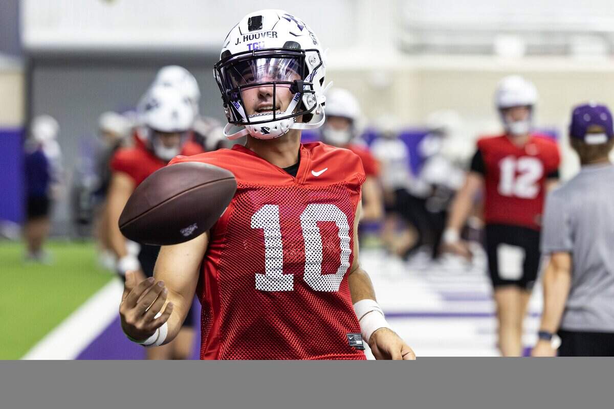 Quarterback Josh Hoover flips a ball in his right hand while wearing practice uniform and pads.