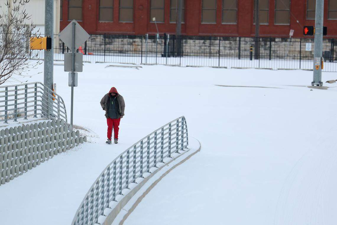 A pedestrian walks along a snow covered Hemphill Street in Fort Worth on Sunday, Jan. 25, 2026.