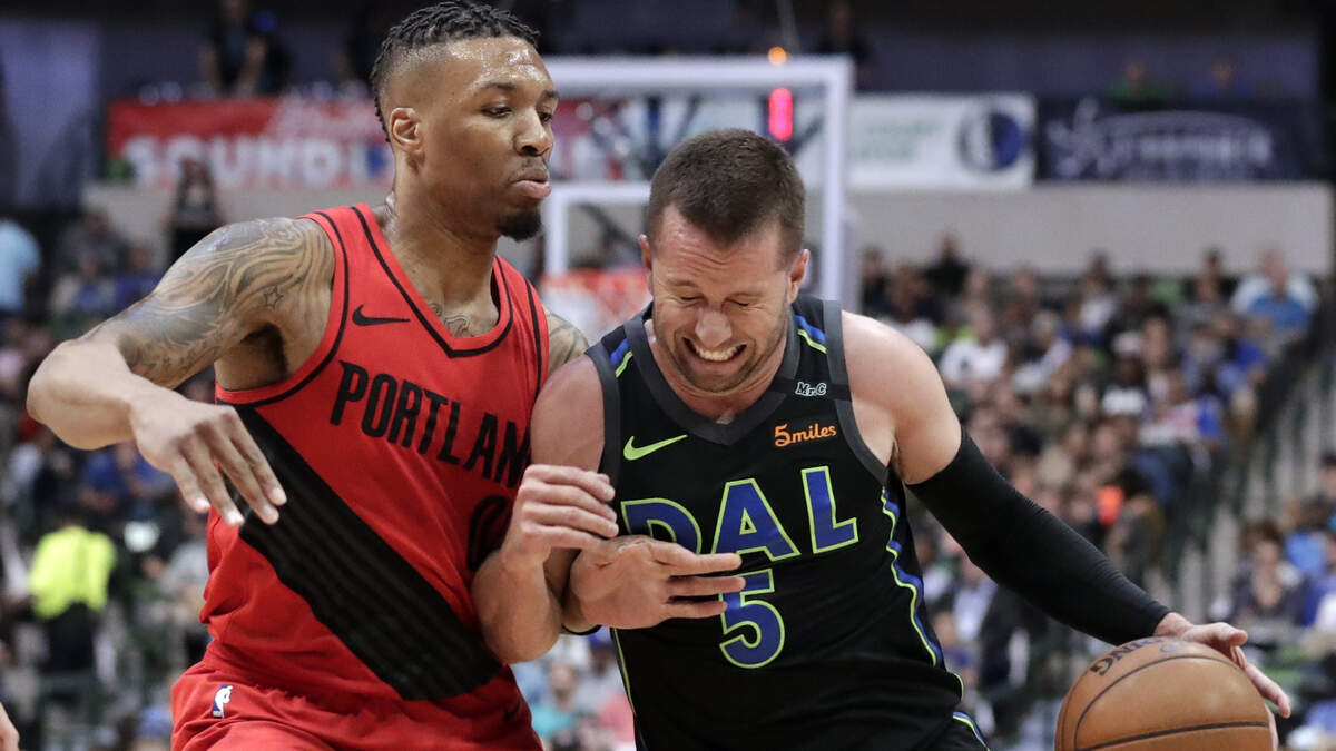 Portland Trail Blazers guard Damian Lillard (0) defends as Mavericks guard J.J. Barea (5) drives to the basket in the first half of Tuesday's game in Dallas.
