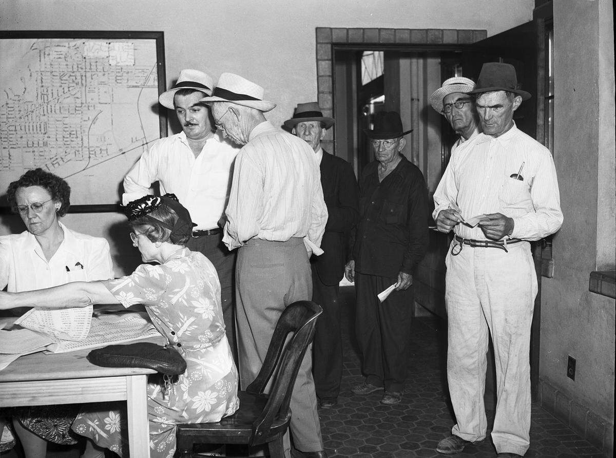 Aug. 5, 1944: Voters crowded to the polls in numbers early for Saturday’s local option election, in contrast to the light vote at the first primary. Two women are sitting a table reading from a long list of names. Six men are standing around the room waiting their turn to cast their ballots.