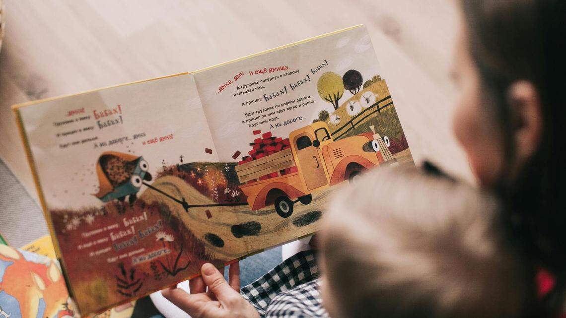 Stock image of a woman reading a book to a toddler.