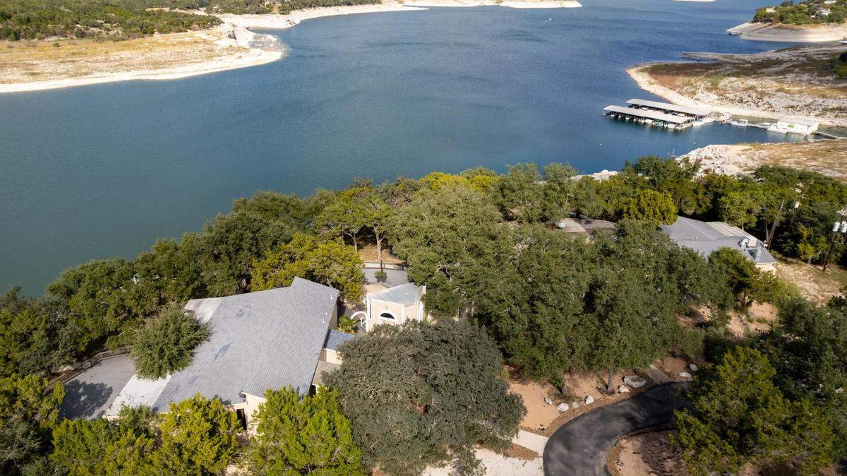 An aerial view of a property on a cliff over Medina Lake in Texas that is listed for $2.5 million. The property has been built around two “mature trees” that are indoors.