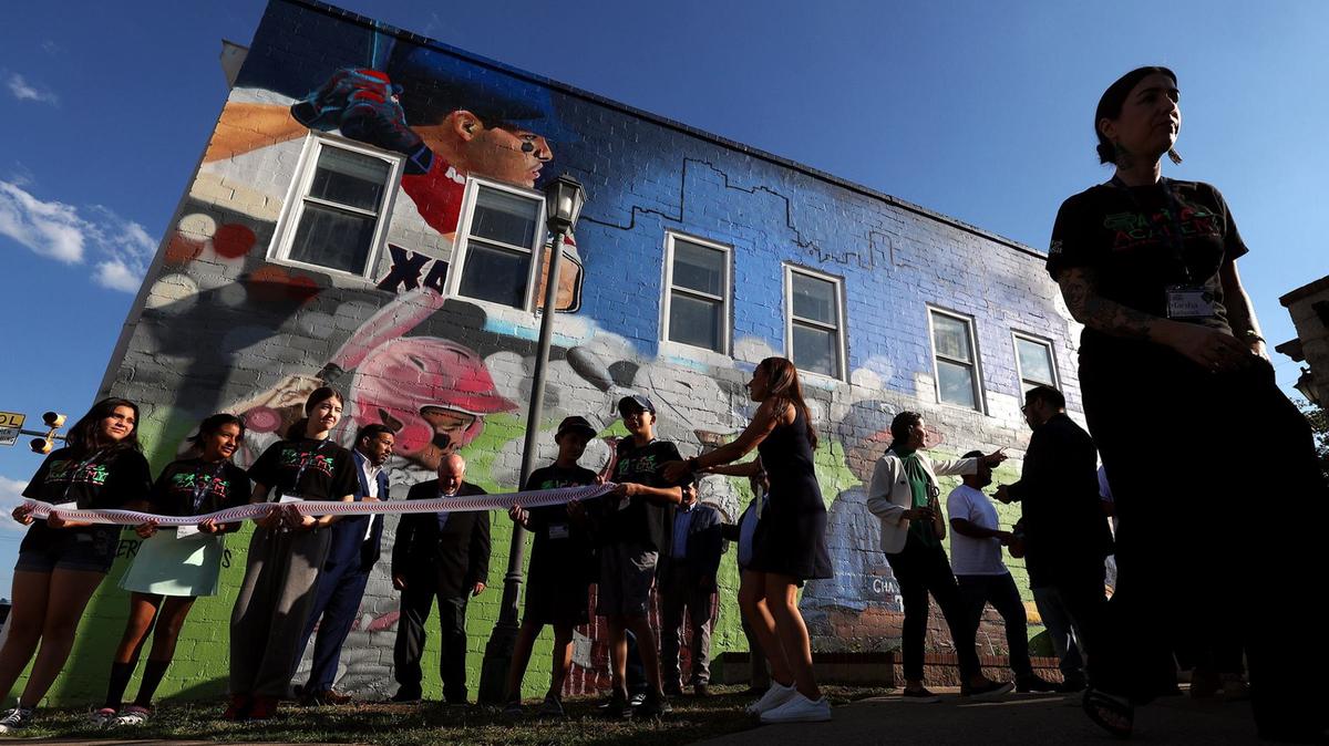 Children of the Artes de La Rosa Cultural Center for the Arts gather for a ribbon cutting during an event to unveil a mural celebrating MLB All-Star Week and Latino softball and baseball players on Wednesday in Fort Worth.