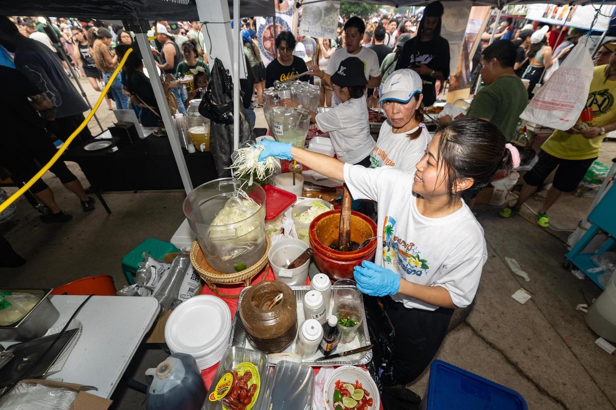 Soy Souyabong makes papaya salad for a customer in their Lao/Thai Food Stand on the third day of the Lao New Year festival at Wat Lao Thepnimith Temple in Saginaw on Sunday, April 27, 2025.