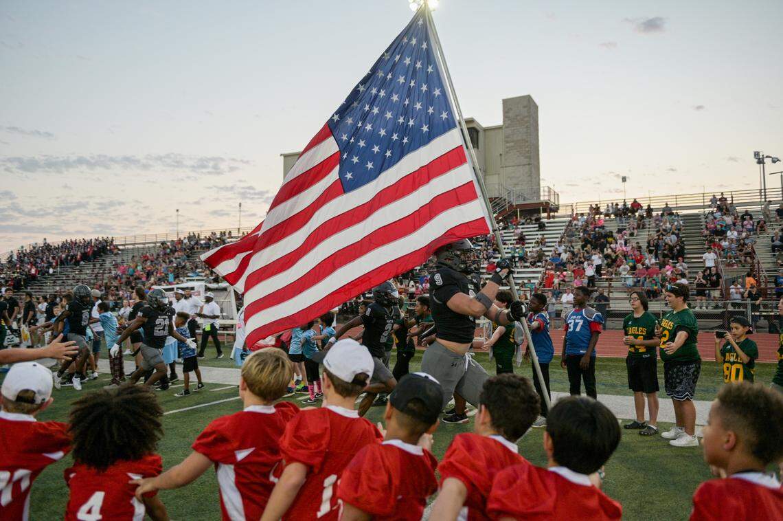 Martin Warrior defensive lineman Jesse Ford (9) runs down the field with the American Flag prior to a UIL football game against Bowie High School at Cravens Field in Arlington, Texas on Friday, Oct. 11, 2024