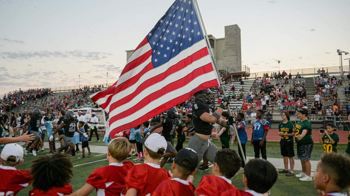 Martin Warrior defensive lineman Jesse Ford (9) runs down the field with the American Flag prior to a UIL football game against Bowie High School at Cravens Field in Arlington, Texas on Friday, Oct. 11, 2024