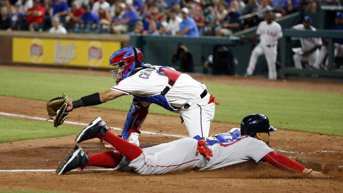 Boston Red Sox Mookie Betts, bottom, slides safely into home in front of Texas Rangers catcher Robinson Chirinos, top, during the seventh inning of Saturday's game in Arlington. Betts took advantage of outfielder Jurickson Profar's indecision on an outfield fly ball.