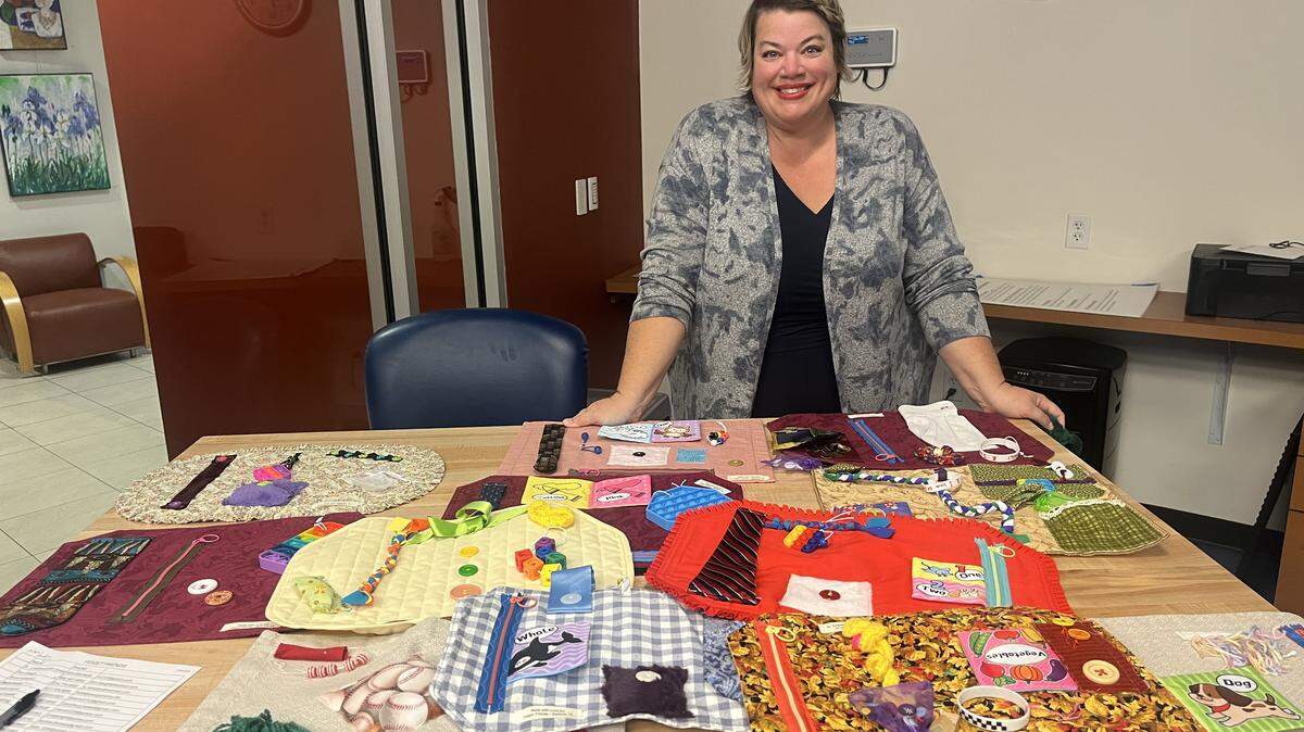 Lindsey Lyons Jones poses with fidget mats for Alzheimer’s patients. Lyons Jones founded a group that meets monthly to make fidget mats for local memory care centers.