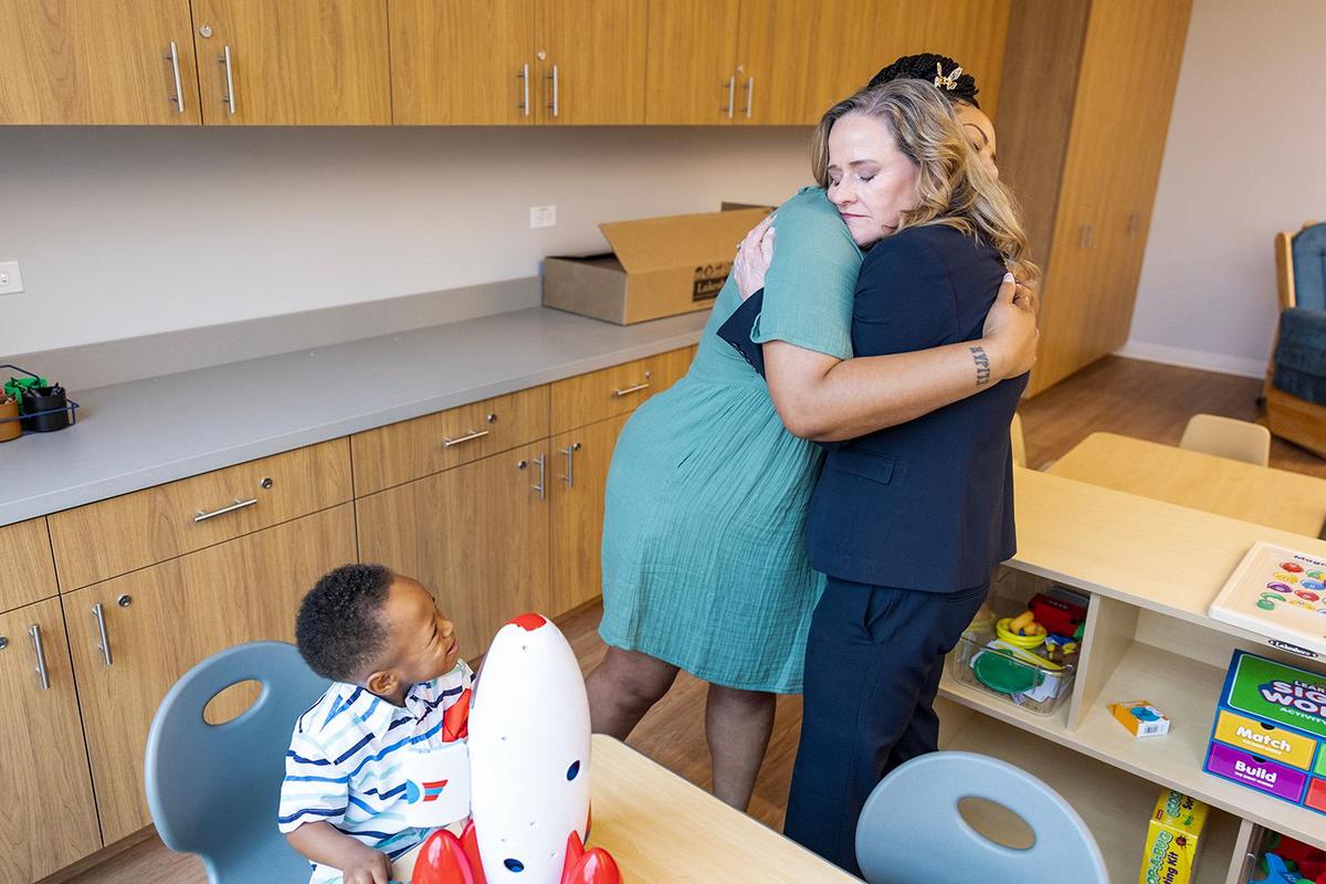Carol Klocek, right, CEO of the Center of Transforming Lives, hugs a Tanisha Thomas, a client of the organization, while Thomas’ son Kingston, 3, watches in one of the family play rooms after the grand opening ceremony of the Center for Transforming Lives’ new Riverside Campus in the Morningside neighborhood of Fort Worth on Friday, May 2, 2025.