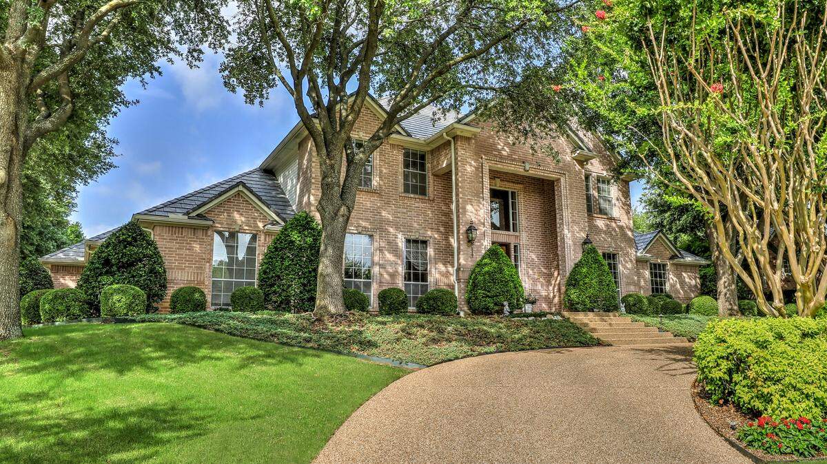 The home at 6108 Annandale Drive is located on a cul-de-sac with manicured landscaping and towering trees.