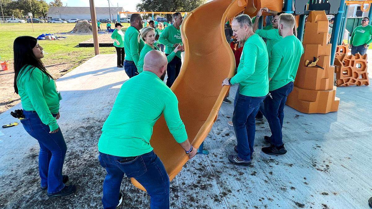 A group of Kellanova employees attach a slide to a new playground at David K. Sellars Elementary School on Tuesday.