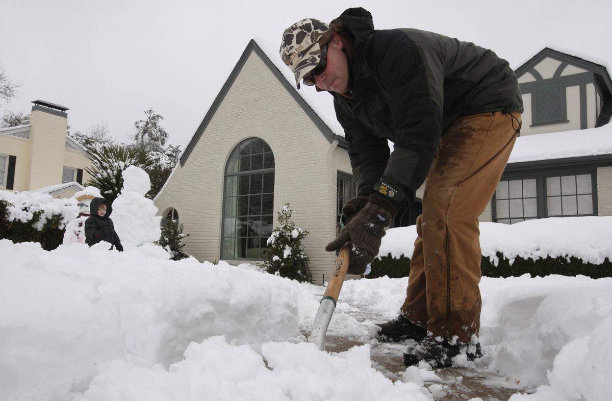 Michael Tappan Bailey, 2, plays in the snow while his father Tappan shovels snow from the front walk of the home in the Monticello neighborhood, Friday, February 12, 2010.