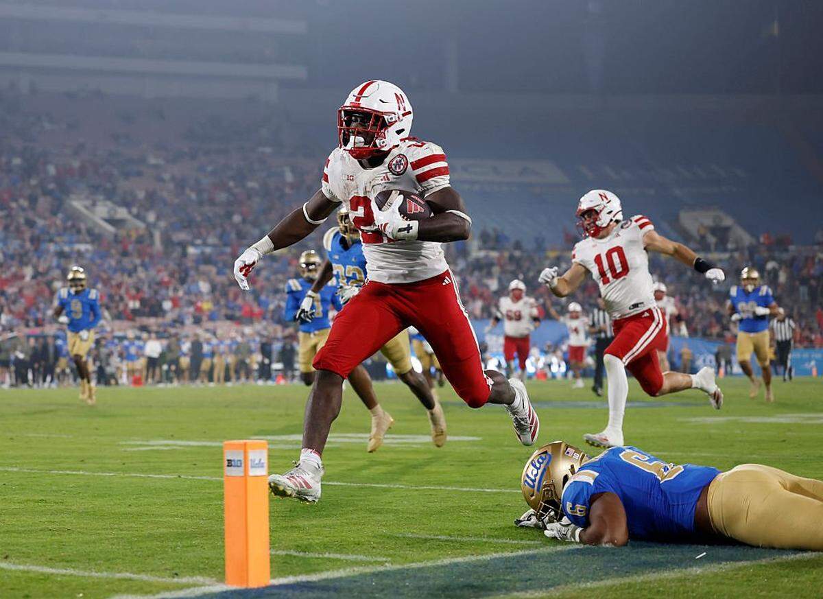 PASADENA, CALIFORNIA - NOVEMBER 08: Emmett Johnson #21 of the Nebraska Cornhuskers runs past Jonjon Vaughns #6 of the UCLA Bruins for a touchdown, to take a 28-7 lead, during a 28-21 win over the UCLA Bruins at Rose Bowl Stadium on November 08, 2025 in Pasadena, California. (Photo by Harry How/Getty Images)