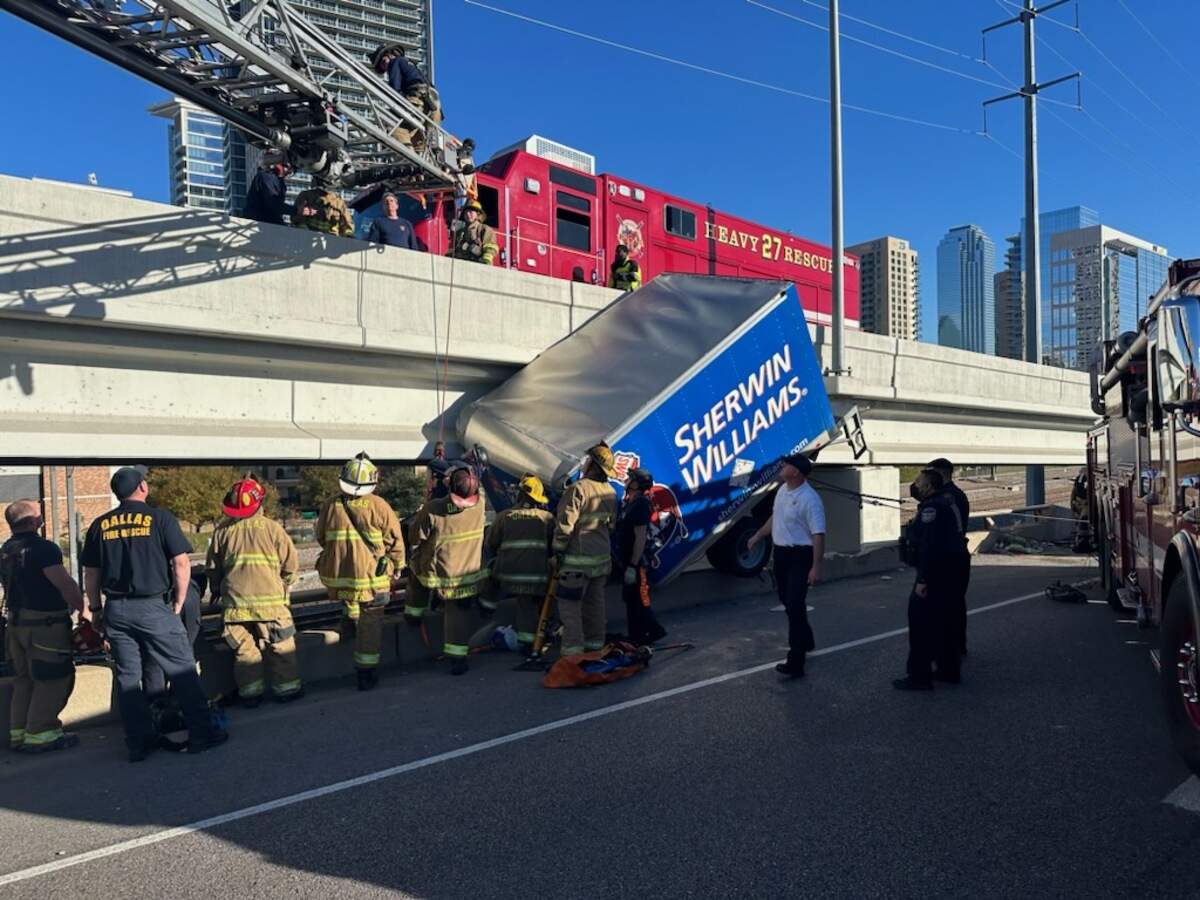 First responders work to rescue a driver in a Sherwin-Williams truck hanging off a bridge on northbound Interstate 35 near Victory Avenue in Dallas County on Monday afternoon.