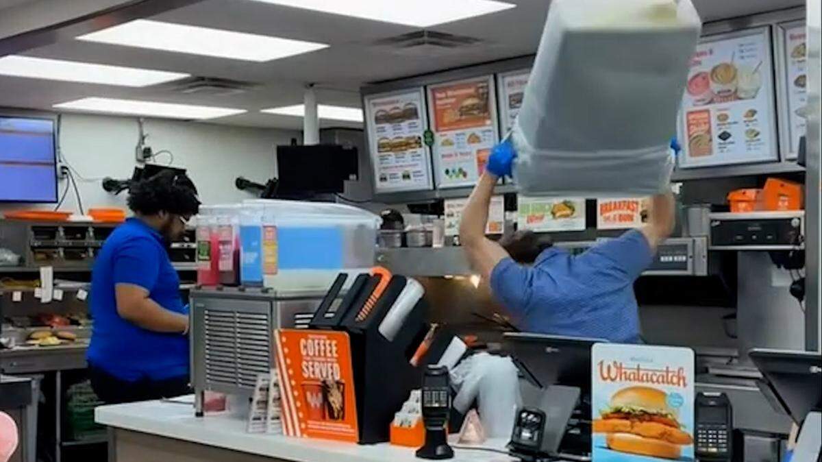 In a screenshot from witness video, the manager of a Paris, Texas Whataburger restaurant raises a garbage can over his head as he attempts to fend off an assailant on Feb. 22.