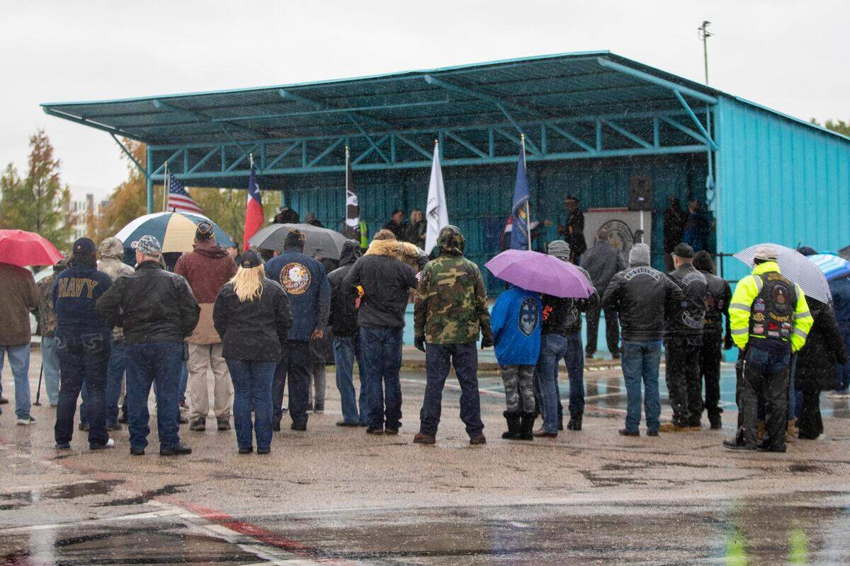 Dozens of people gather to listen to the introduction ceremony for the Veterans Day Parade in Fort Worth on Friday, Nov. 11, 2022. Despite rain, hundreds of participants marched down North Forest Park Boulevard, waving American flags and signing a medley of military songs.