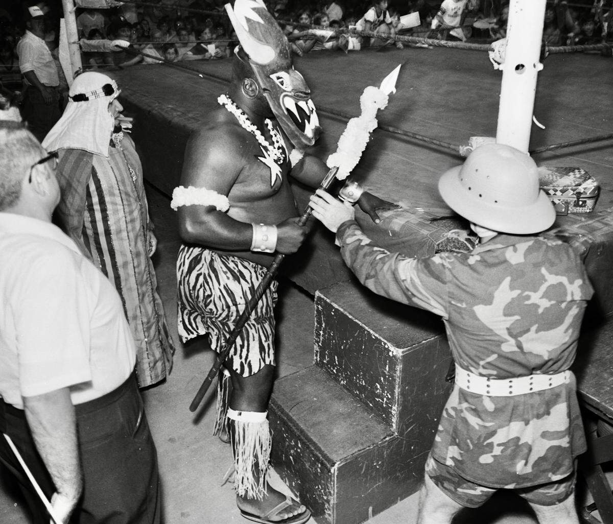 Manager Skandor Akbar stands behind “Kamala the Ugandan Giant” (James Harris), and his handler “Kim Chee” at ringside during wrestling at Will Rogers Coliseum in Fort Worth, about 1983.