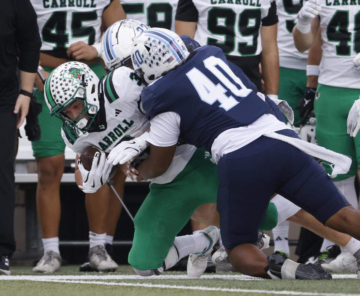 Southlake running back Davis Penn (3) is brought down on the Dragon sidelines by L.D. Bell defensive back Caden Digiulio (27) and outside linebacker Sione Fiefia (40)during the first half of a UIL football game between Carroll and L.D. Bell at Pennington Field in Bedford, Texas, Friday, October, 24, 2025.