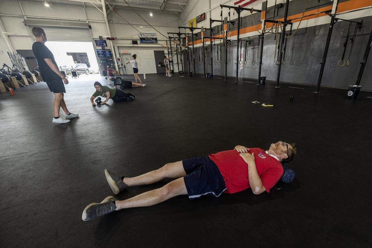 Kevin Kirkland lying on his back in athletic gear in a large room with workout equipment.