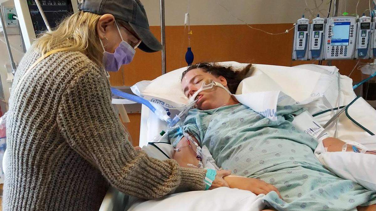 Peggie Griggs holds her granddaughter’s hand at JPS Hospital, where Kelly Masten was transferred after 10 days at the Tarrant County Jail. Masten’s family said she has a seizure disorder that went untreated during her incarceration.