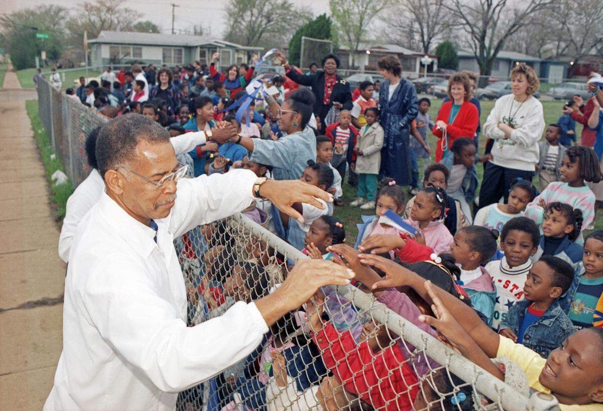 Robert Hughes, head basketball coach at Dunbar High School, accepts good-luck wishes from a crowd of students, parents, and teachers from Maudrie Walton Elementary School before the team’s departure to Austin for the state championship tournament.