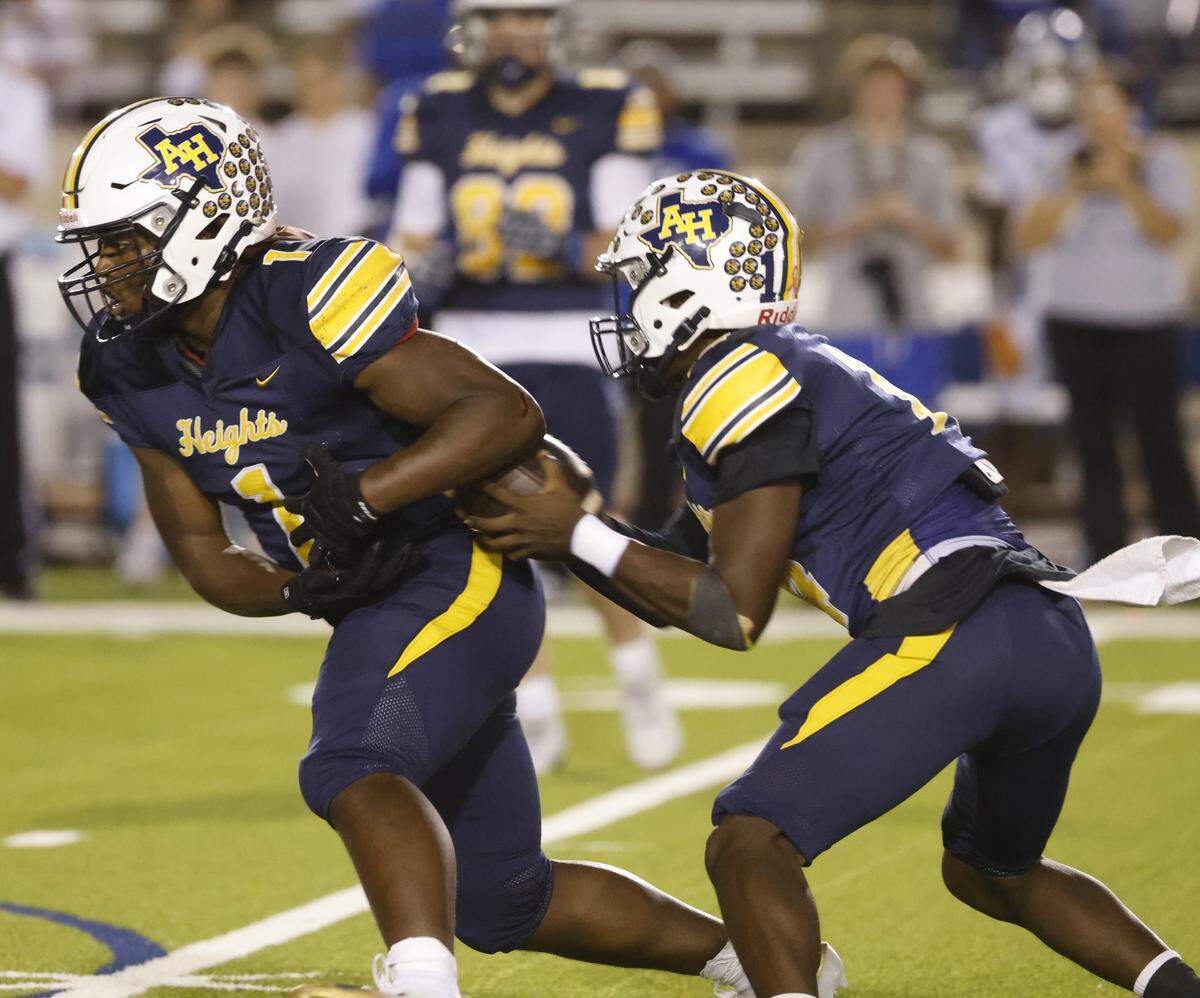 Arlington Heights quarterback Carmelo Carter (14) pulls the ball back from running back Carson James (1) for a keeper during the first half of a UIL Conference 5A D1 Bi-District playoff game between Arlington Heights and Brewer at Farrington Field in Fort Worth, Texas, Friday, Nov. 14, 2025.