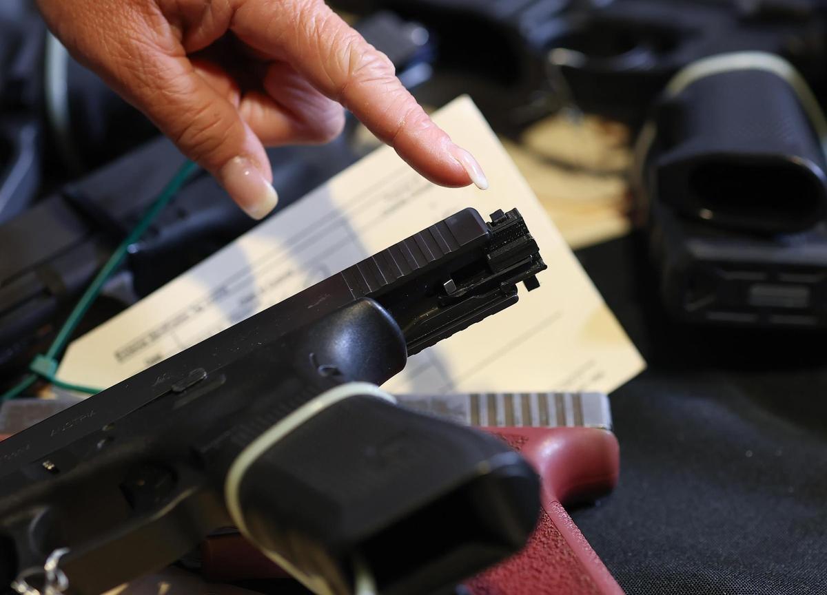 Sara Abel, the public information officer for the Bureau of Alcohol, Tobacco, Firearms and Explosives (ATF) Dallas Field Division, points out a machine gun conversion device on a pistol during a press conference on Wednesday, June 18, in Fort Worth.