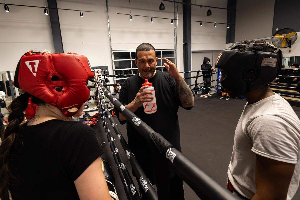 Anahi Olmos, left, and Nick Brown, right, listen to secondary coach Tomás Vasquez as he teaches them proper boxing technique at the Diamond Hill Community Center in Fort Worth.