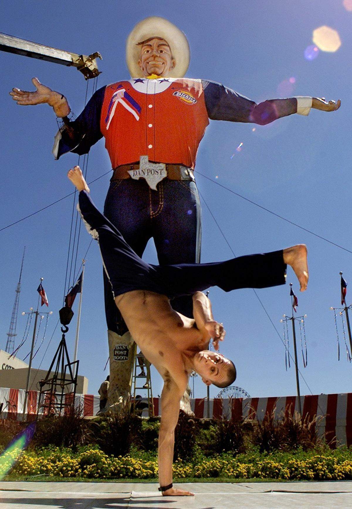 Sept. 27, 2001: The last day of preparation at the Texas State Fair in Dallas saw midway game booths, concessions, and fair talent busy making preparations and rehearsing for tomorrow’s opening day. Cosme Taturana, a member of Capoeira Brazil, a gymnastic group, rehearses on the Big Tex Circle Stage, with the fair’s most recognized symbol, Big Tex, behind him.
