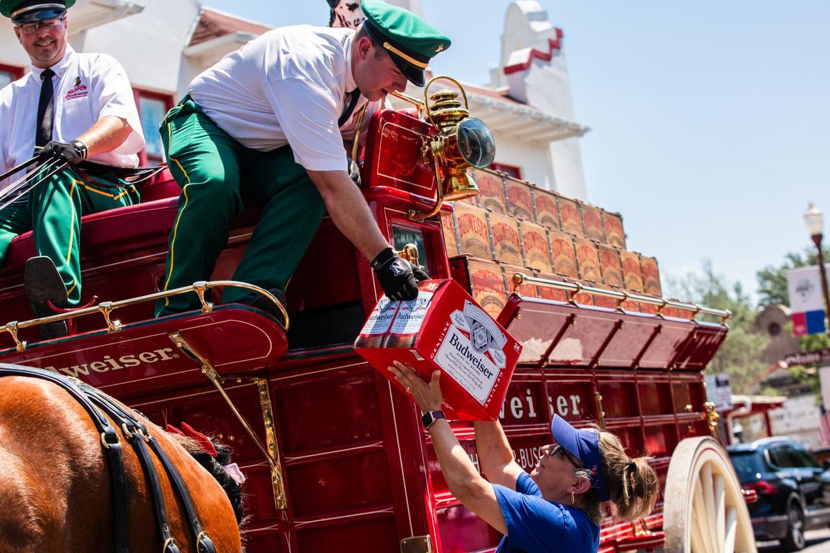 Budweiser Clydesdale handler Alex Smith, left hands a case of beer to The Love Shack supervisor Vicky Scruggs, right on Friday, July 12 at the Fort Worth Stockyards. Budweiser was the main sponsor for the clydesdales and delivered beer to attendees celebrating the upcoming All-star game.