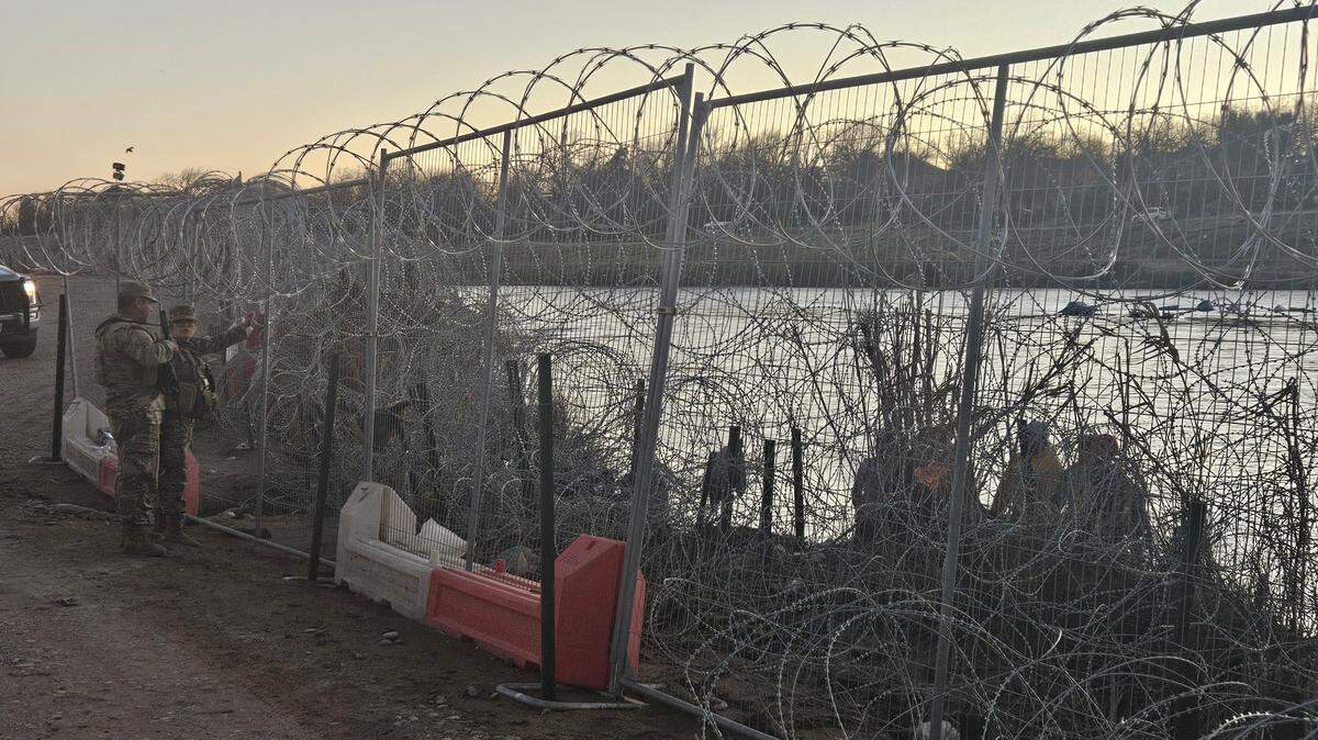 A member of the Texas National Guard speaks in Spanish to young migrants trying to cross through the wire fencing at the border in Eagle Pass, Texas.