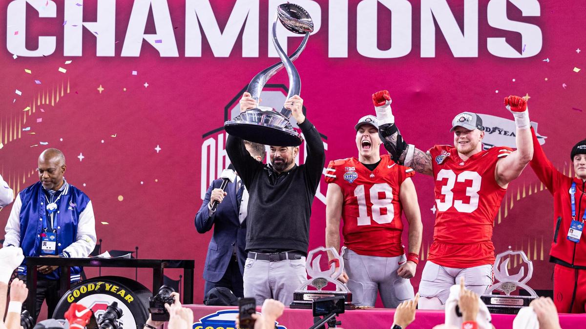 Ohio State Head Coach Ryan Day holds up the Cotton Bowl Championship trophy on stage with quarterback Will Howard (18) and defensive end Jack Sawyer after Ohio State defeated Texas 28-14 in the College Football Playoff semifinal game at AT&T Stadium in Arlington on Friday, Jan. 10, 2025.