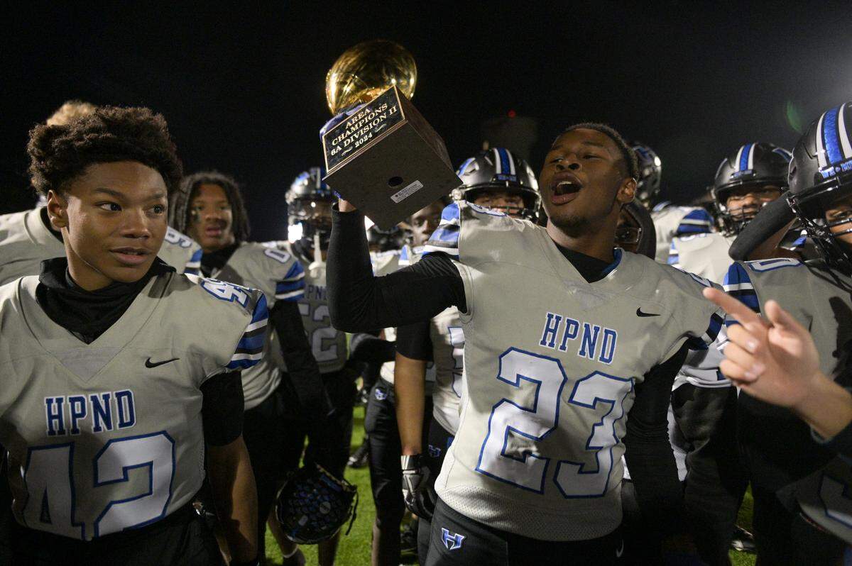 Hebron hawk linebacker Joshua Turner (23) lifts the Arena Championship trophy during a UIL football playoff game against Bowie High School at Mustang-Panther Stadium in Grapevine, Texas on Friday, Nov. 22, 2024.