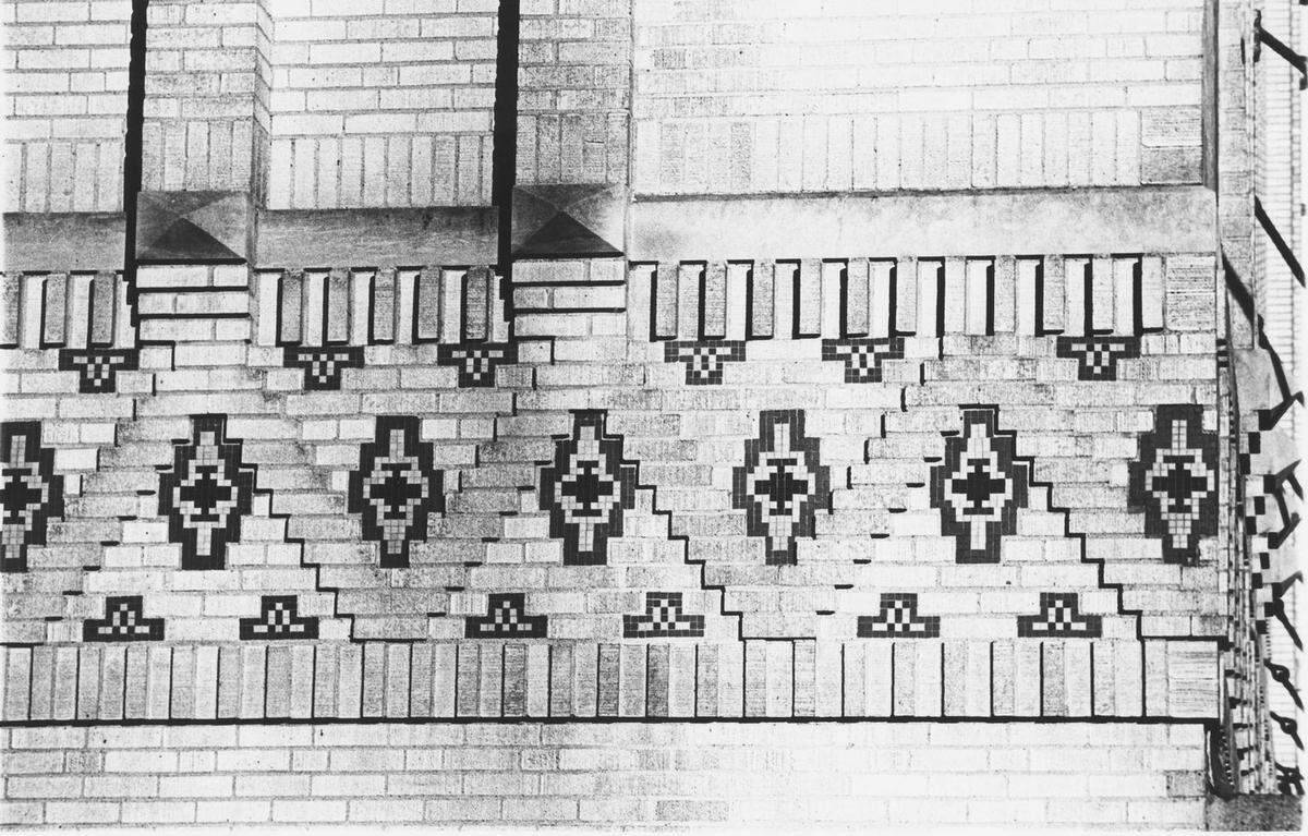 Zigzag brickwork and Native American designs in colored tile form a decorative band around the second floor of the 91-year-old Texas & Pacific Warehouse.&nbsp; Air pollution has darkened the buff-colored brick.&nbsp;