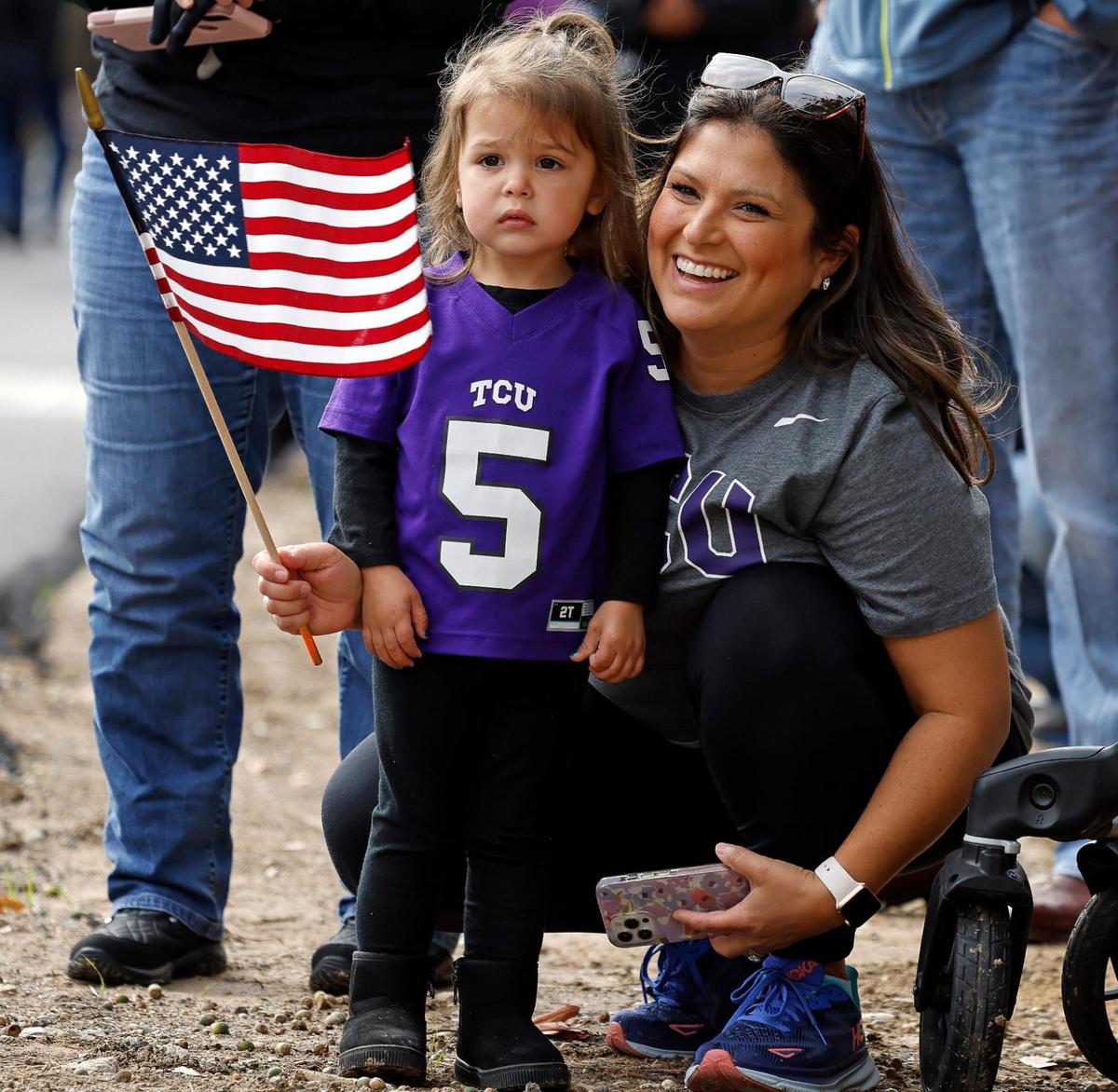 Ashley Schumacher and Hailey, 2, watch the Army Band pass during the 2023 Tarrant County Veterans Day Parade.