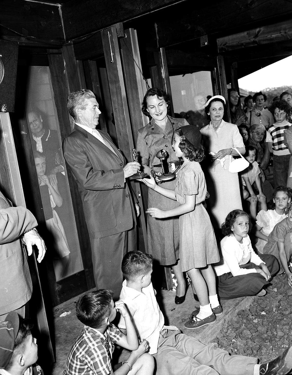 May 25, 1954: Karen Cole, an 8-year-old Brownie, presents an official Girl Scout statuette to Kenneth Davis, who contributed $40,000 to build and furnish a new lodge at Camp Timberlake. Mrs. John M. Scott, Tarrant County Girl Scout Council president, holds a key to the lodge.