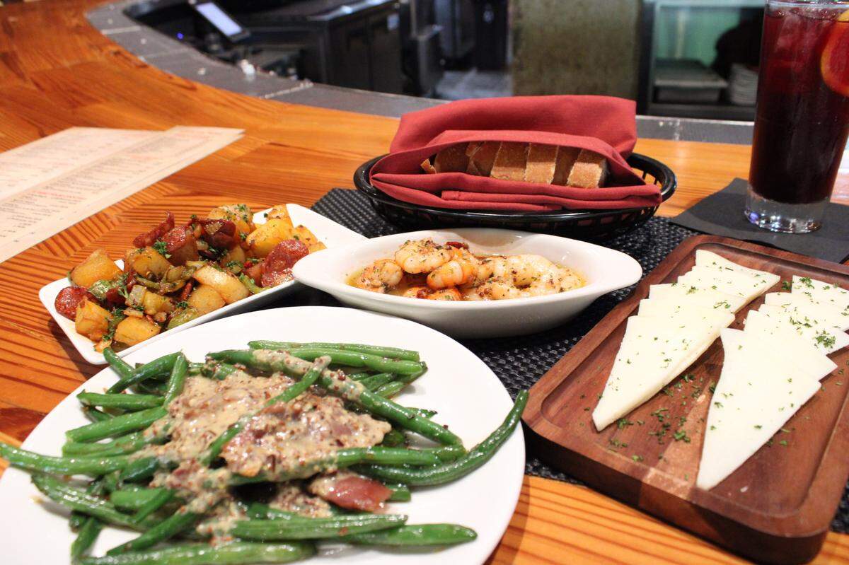 A full meal at Si Tapas of small dishes coming together to make one. Potatoes and chorizo, greenbeans with mustard and ham, shrimp with butter and garlic, and manchego cheese.