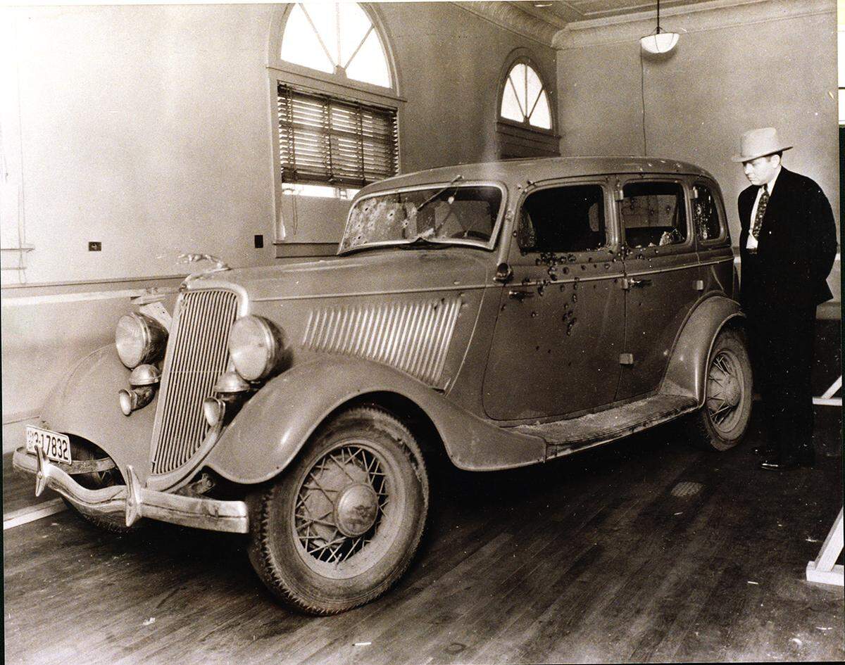 Car used by Bonnie Parker and Clyde Barrow at time of their deaths, May 1934. Sheriff C.D. Little at far right.