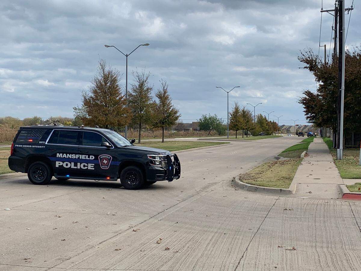 A Mansfield, Texas police vehicle blocks off a neighborhood where a standoff with a barricaded person was ongoing Wednesday after a fatal shooting.